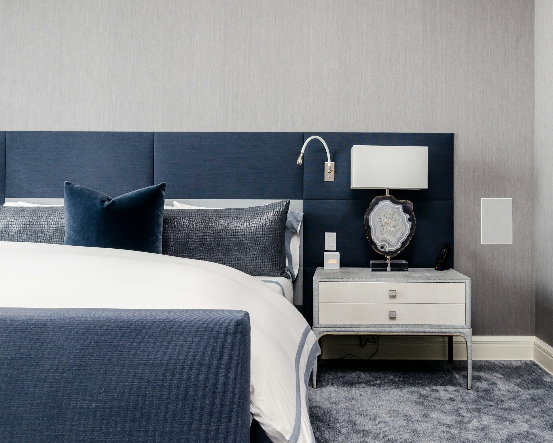 white and clear desk lamp on white wooden nightstand near bed